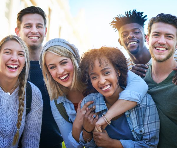 Portrait of a group of diverse students hanging out together outside on campus